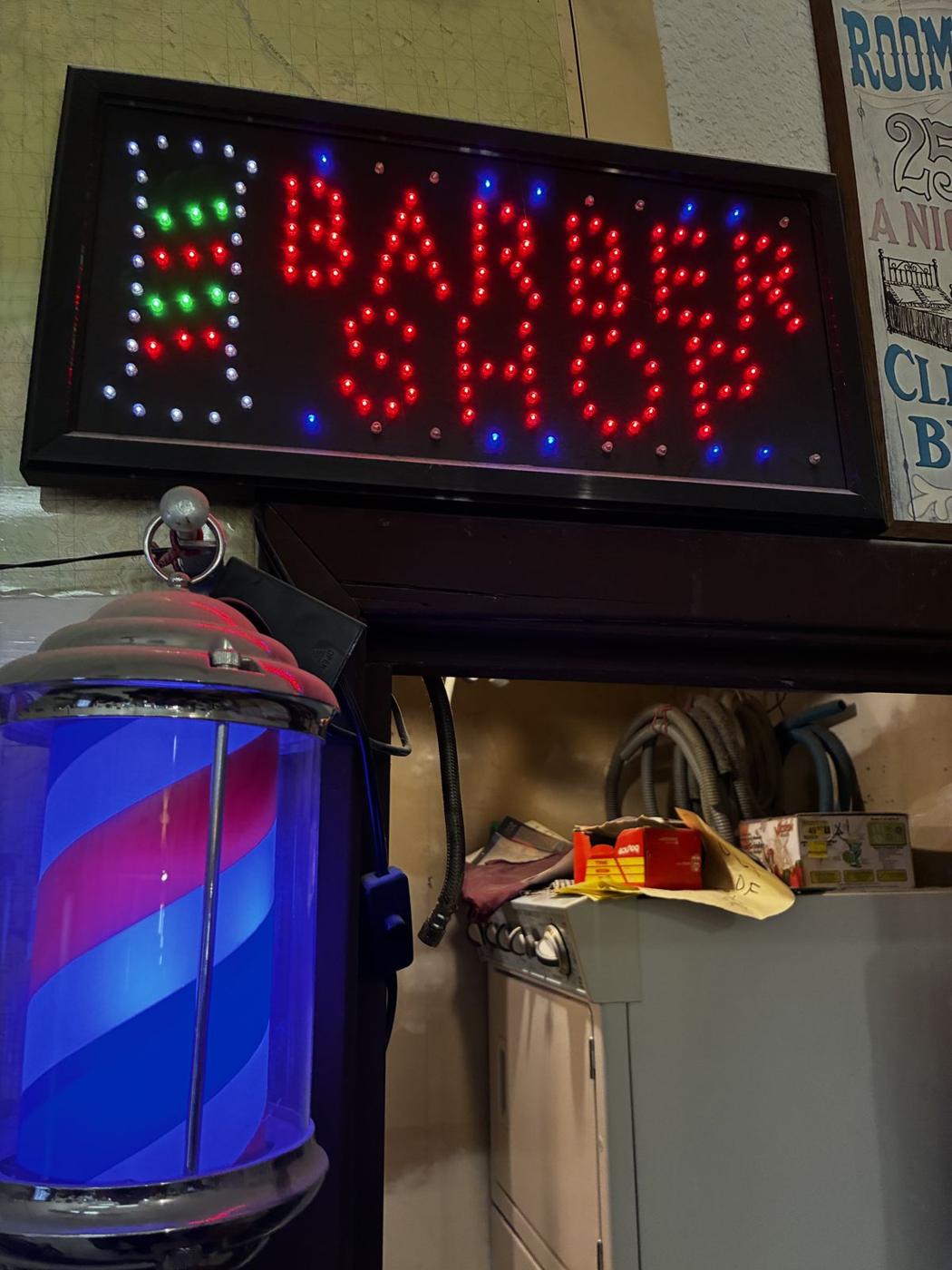 Lit barber pole and LED Barber Shop sign inside the shop