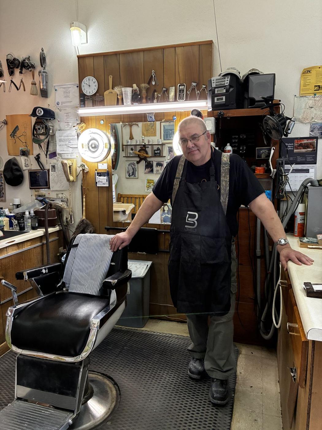 Stan standing beside his barber chair inside the shop